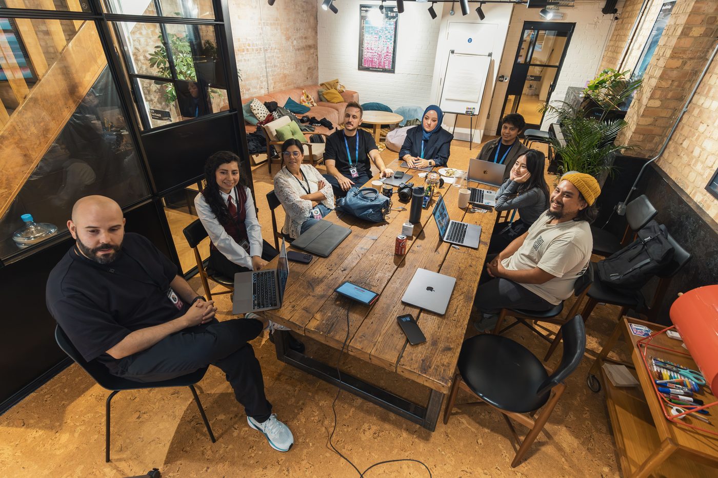 Equipe diversa reunida ao redor de uma mesa, colaborando com notebooks em um escritório moderno.